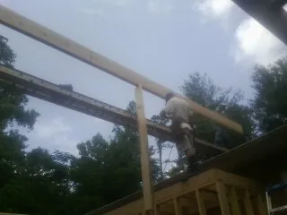 Carpenter setting a ridge beam over a new addition frame — Ice Dam Removal by Roofing Brothers in La Plata