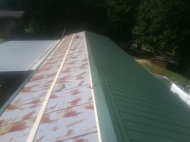 Old rusted panels beside newly installed green metal roofing — Wind Damage Roof Repair by Roofing Brothers in La Plata