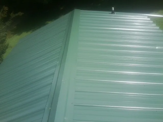 New green metal panels meeting at the ridge of a roof — Flat Roof Repair work by our crew in La Plata