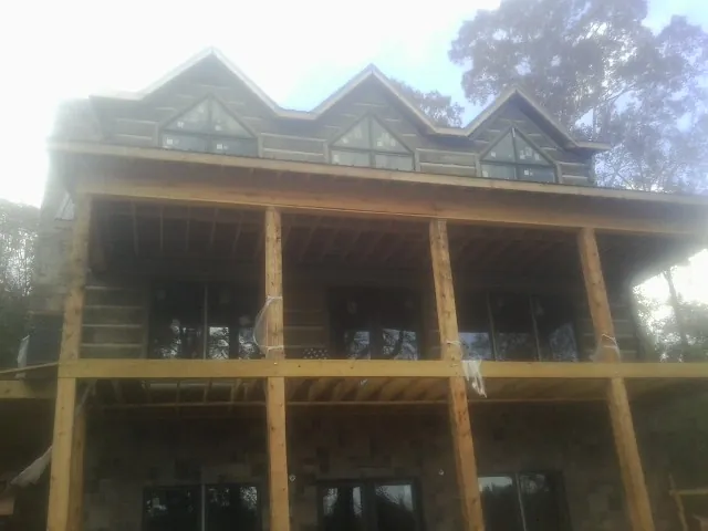 Dormers and porch framing on a large log home under construction — Roof Coating work by our crew in La Plata