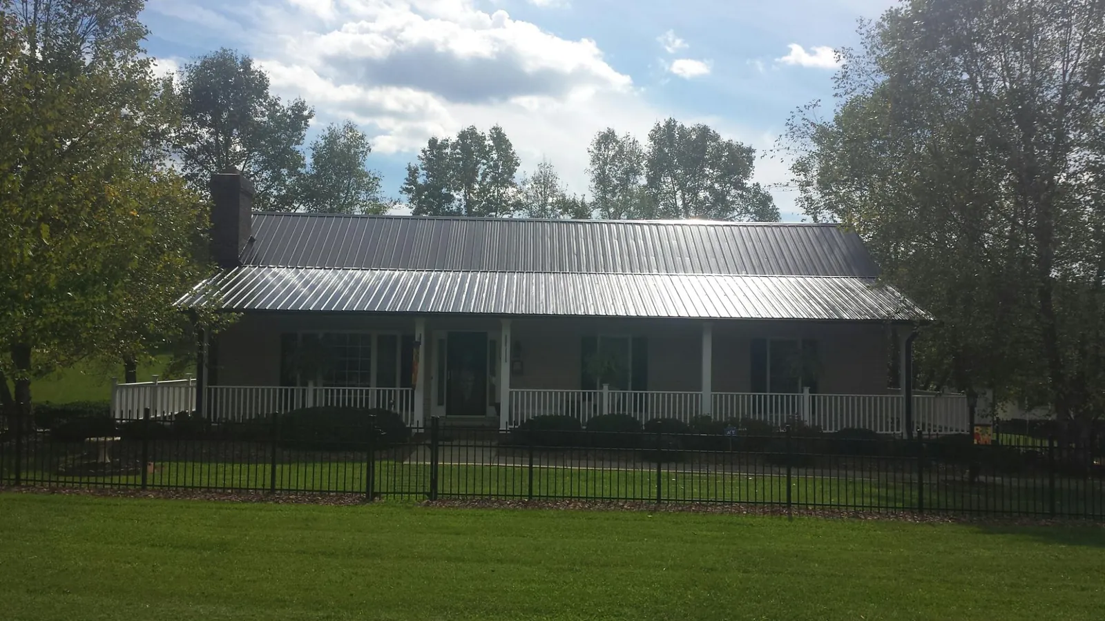 Gray metal roof on a brick ranch with a full width front porch — Gutter Guard Installation work by our crew in La Plata