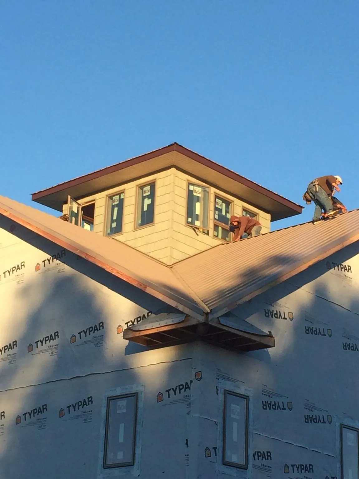 Roofers working around a rooftop cupola on a new metal roof at sunset — Roof Waterproofing in La Plata by Roofing Brothers